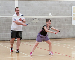 Image of players playing badminton from the perspective of a player receiving a serve.