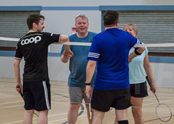 Image of a player playing badminton focused on a player playing a serve.